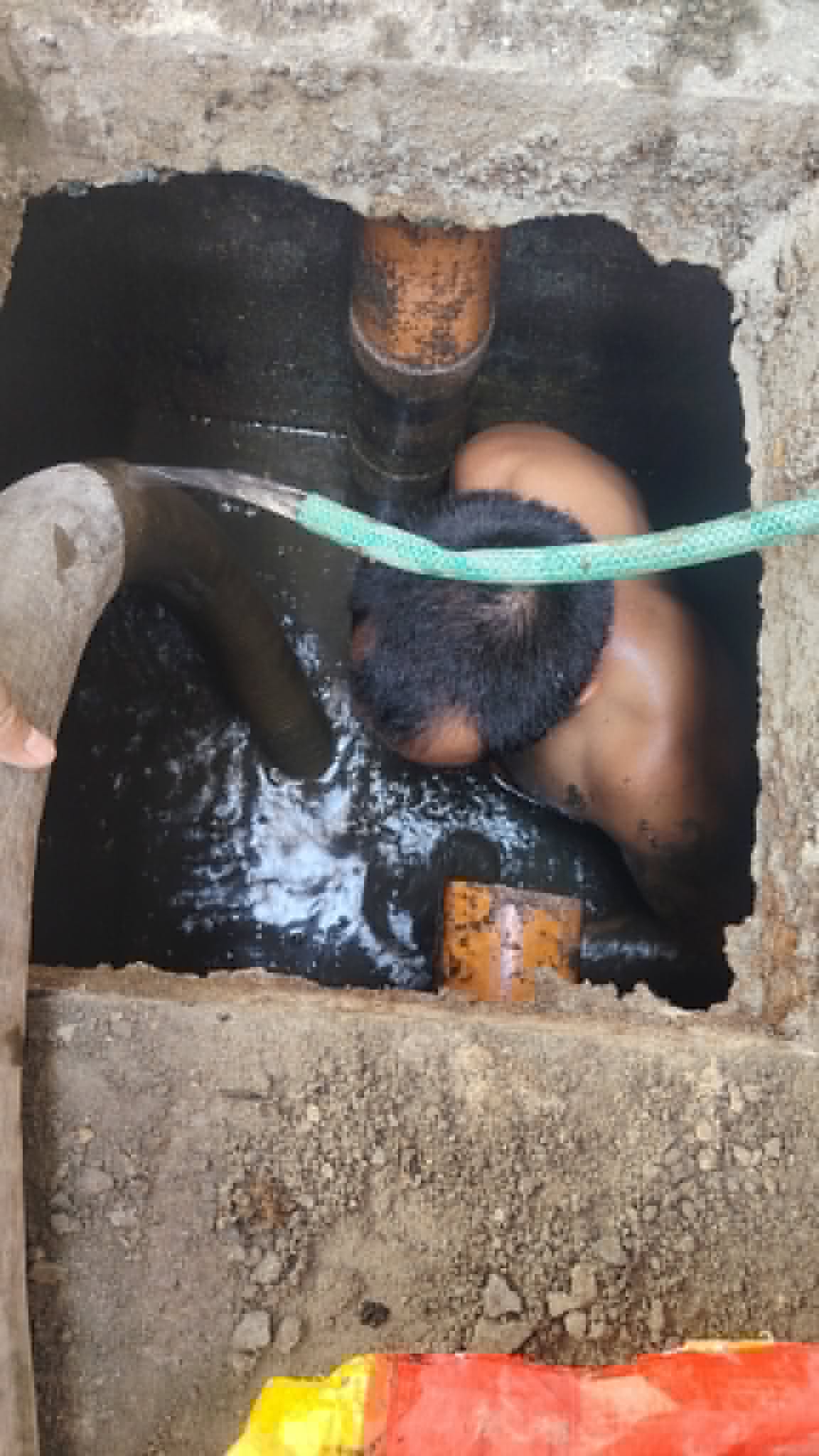 Technician clearing a septic access pipe by hand